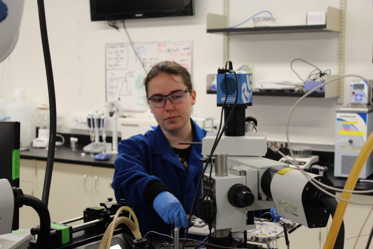 Jelayne, lab technician, working at a microscope